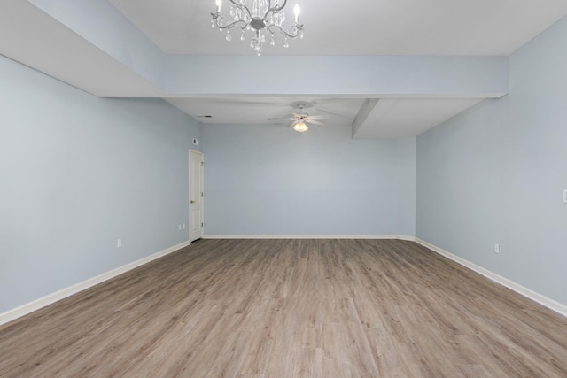 spare room with light wood finished floors, baseboards, and ceiling fan with notable chandelier