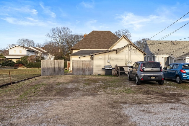 view of home's exterior with roof with shingles and fence