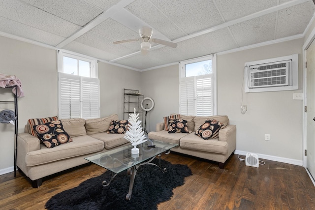 living area featuring a drop ceiling, an AC wall unit, baseboards, and hardwood / wood-style floors