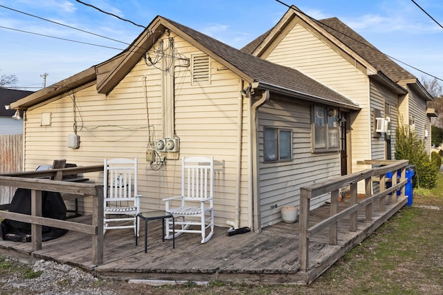 rear view of house featuring a shingled roof and a wooden deck