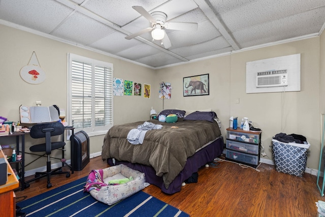 bedroom with a ceiling fan, wood finished floors, baseboards, a wall mounted AC, and a paneled ceiling