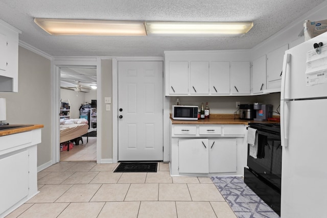 kitchen featuring light tile patterned floors, freestanding refrigerator, white cabinets, a textured ceiling, and black electric range oven