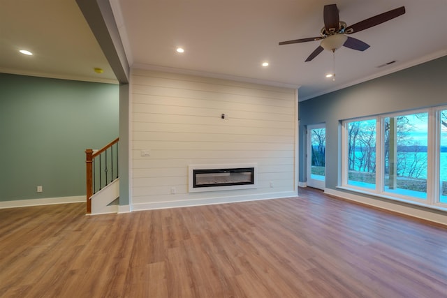 unfurnished living room with ceiling fan, ornamental molding, a fireplace, and light wood-type flooring