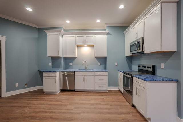 kitchen featuring sink, white cabinetry, crown molding, light hardwood / wood-style flooring, and stainless steel appliances