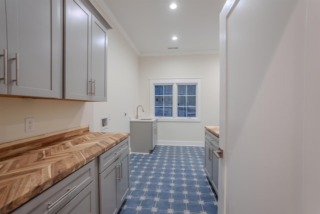 kitchen featuring butcher block countertops, gray cabinets, and ornamental molding