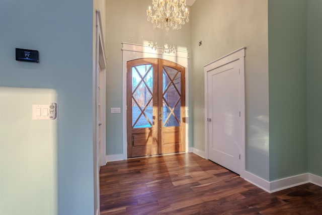 foyer entrance featuring a high ceiling, dark wood-type flooring, a notable chandelier, and french doors