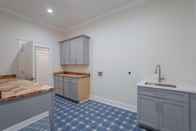 clothes washing area with sink, crown molding, hookup for a washing machine, cabinets, and hookup for an electric dryer