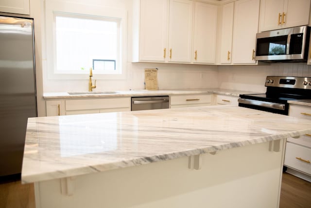 kitchen with sink, dark hardwood / wood-style floors, light stone counters, white cabinetry, and stainless steel appliances