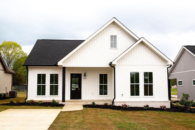 modern farmhouse style home featuring covered porch, a front lawn, and cooling unit