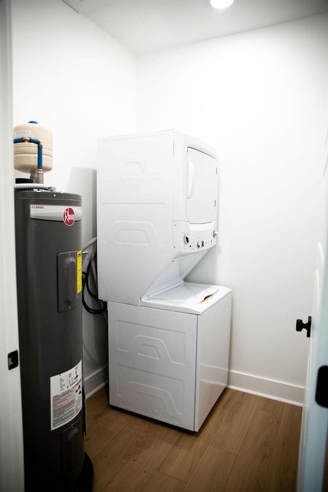 clothes washing area featuring hardwood / wood-style flooring, stacked washer / dryer, and water heater