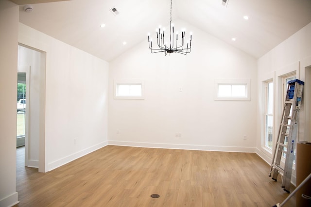 spare room with light hardwood / wood-style flooring, high vaulted ceiling, and a chandelier