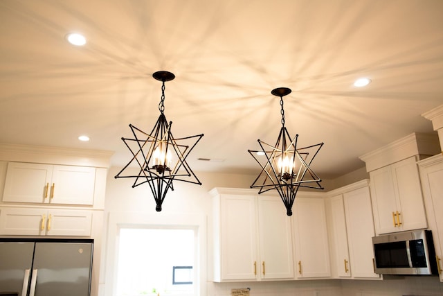 details with white cabinetry, hanging light fixtures, a notable chandelier, backsplash, and appliances with stainless steel finishes