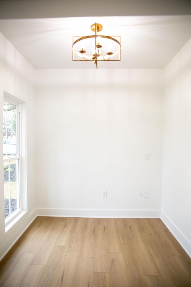 unfurnished room with light hardwood / wood-style flooring and a chandelier