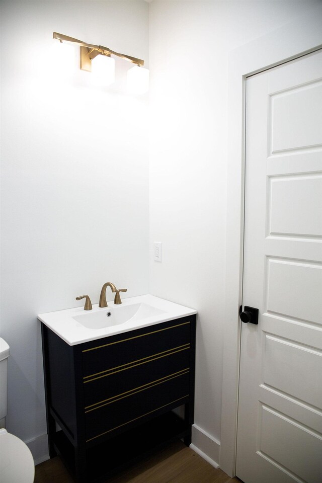 bathroom with vanity, toilet, and wood-type flooring