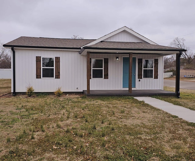 view of front of property with a porch, a front yard, and a shingled roof