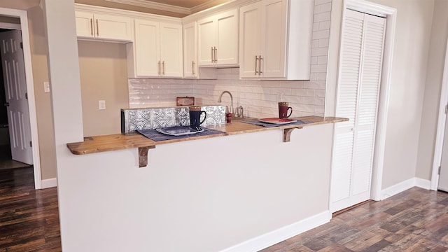 kitchen with dark wood-style floors, a breakfast bar area, baseboards, and decorative backsplash