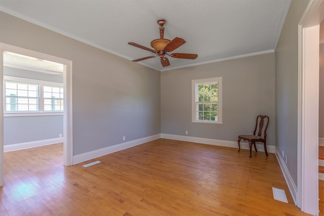 unfurnished room with ornamental molding, light wood-style floors, ceiling fan, baseboards, and a textured ceiling