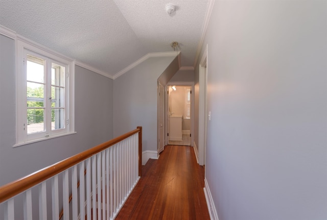 corridor with hardwood / wood-style floors, ornamental molding, baseboards, a textured ceiling, and lofted ceiling