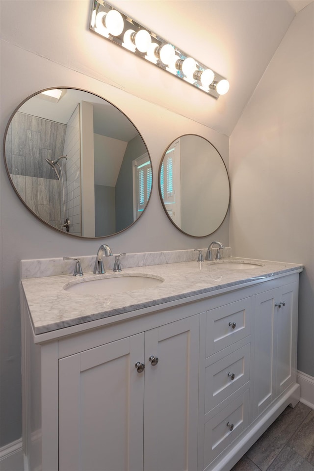 bathroom with lofted ceiling, double vanity, and wood finished floors