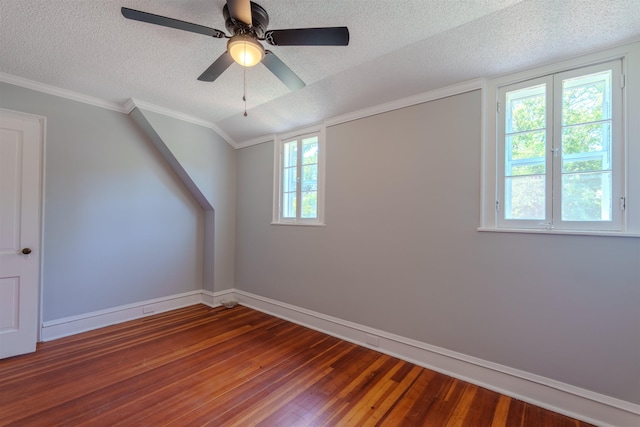additional living space with a textured ceiling, hardwood / wood-style floors, baseboards, a ceiling fan, and vaulted ceiling