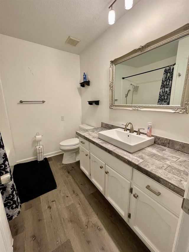  - full bath featuring wood finished floors, vanity, a textured ceiling, and curtained shower