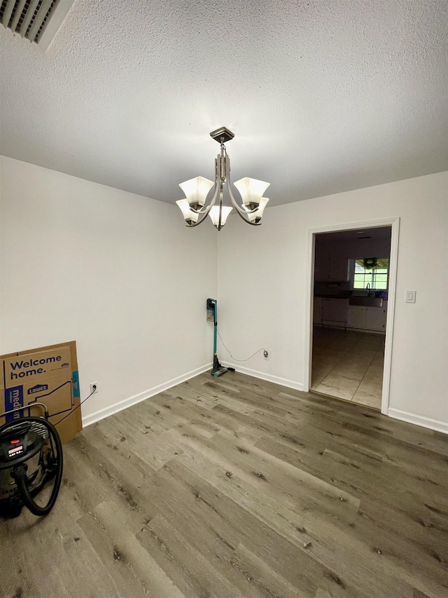  - unfurnished dining area with wood finished floors, a textured ceiling, and a chandelier