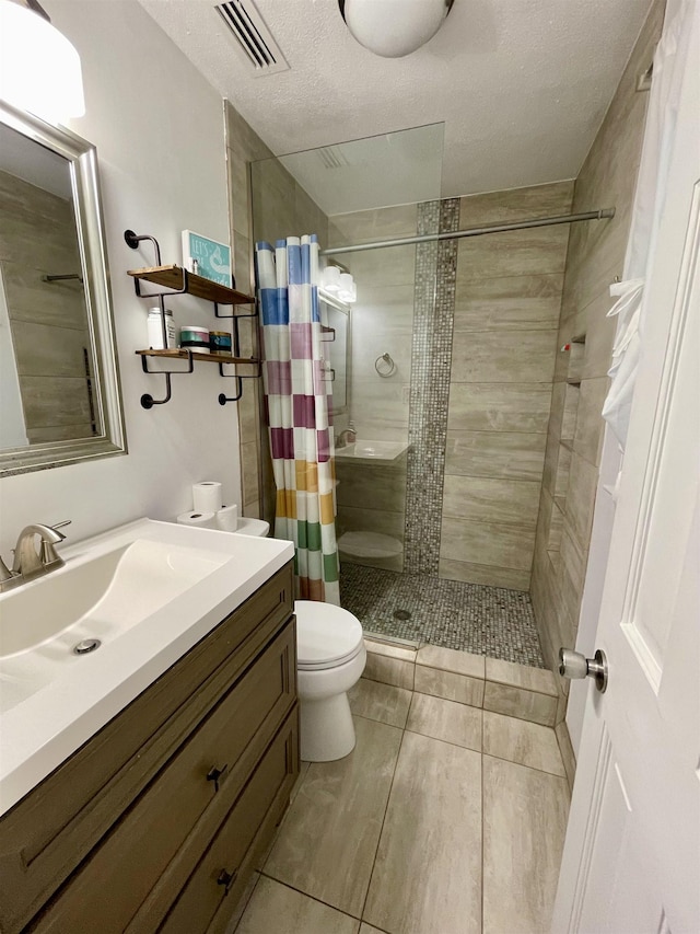  - full bath with vanity, a tile shower, a textured ceiling, and tile patterned flooring