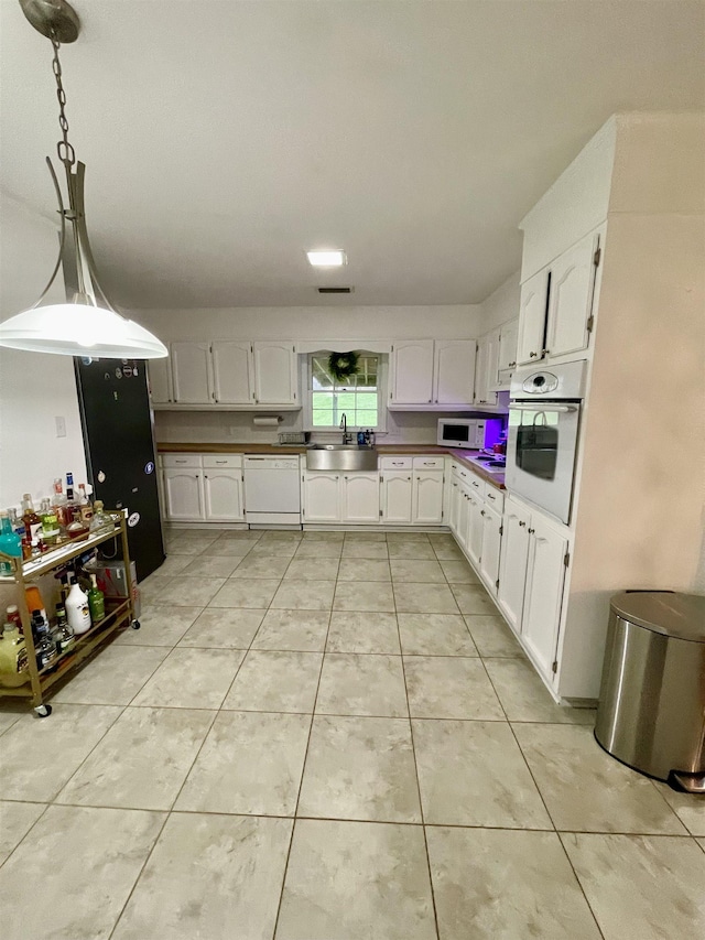  - kitchen featuring white appliances, white cabinetry, light tile patterned floors, and pendant lighting