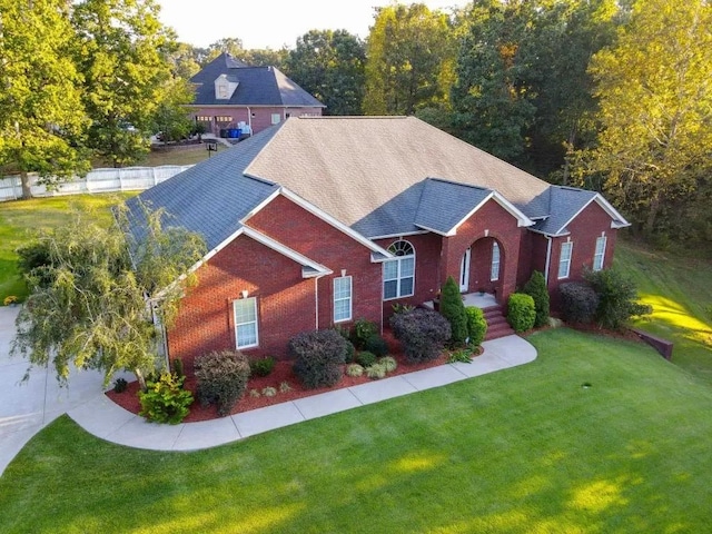 view of front of house with brick siding, a front yard, and a shingled roof