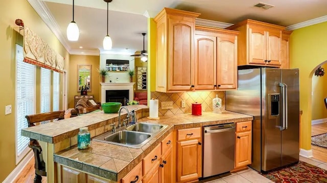 kitchen featuring stainless steel appliances, a sink, visible vents, open floor plan, and tile counters