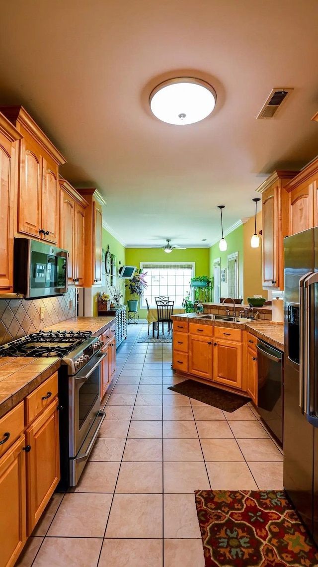 kitchen featuring light tile patterned floors, stainless steel appliances, visible vents, light countertops, and decorative light fixtures