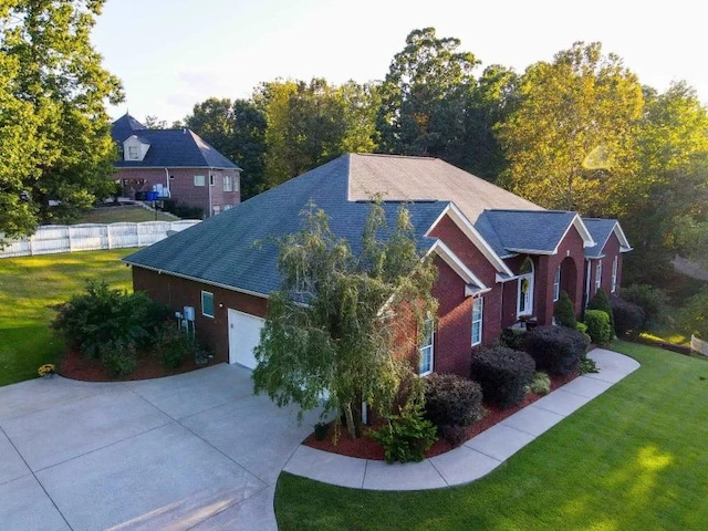 view of front of house with brick siding, concrete driveway, fence, a garage, and a front lawn