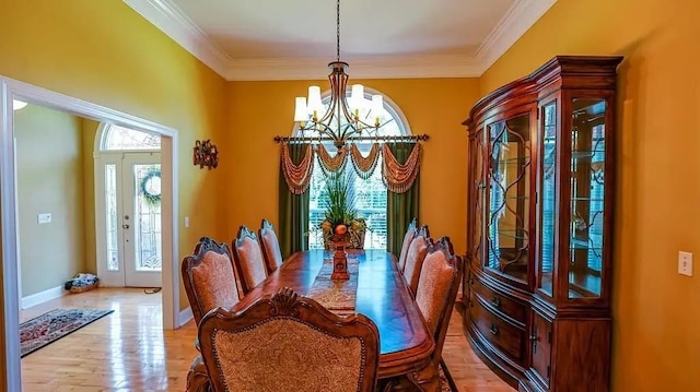 dining area with light wood-type flooring, crown molding, baseboards, and an inviting chandelier