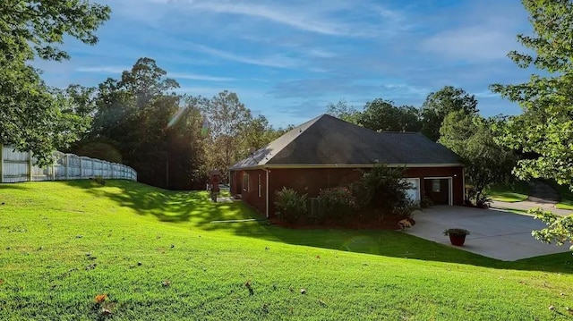 view of property exterior featuring a garage, concrete driveway, fence, a yard, and a patio area