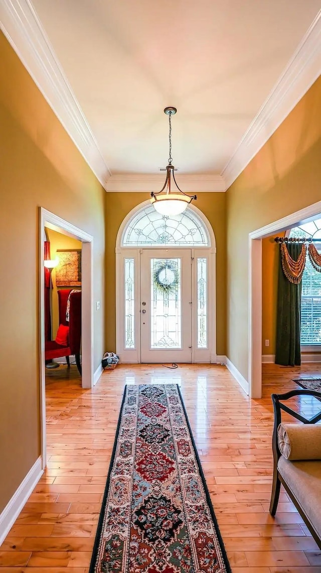 entrance foyer featuring ornamental molding, light wood-style floors, and baseboards