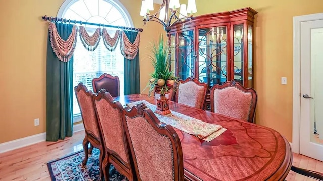 dining space with baseboards, wood finished floors, and a notable chandelier