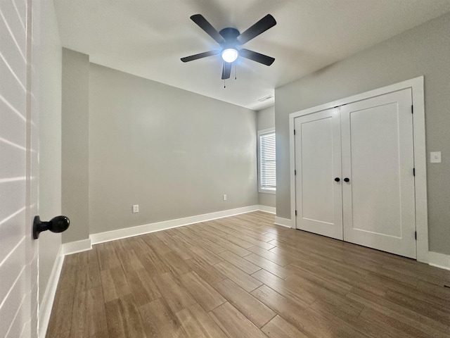 unfurnished bedroom with light wood finished floors, a closet, baseboards, and a ceiling fan