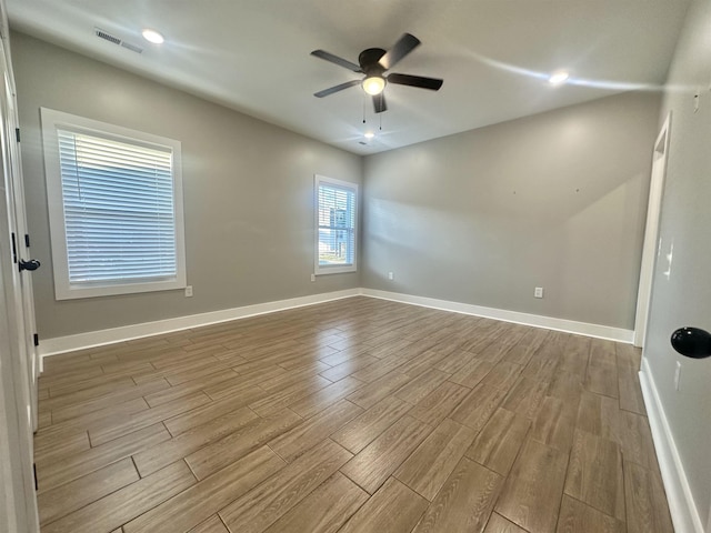 unfurnished room featuring ceiling fan, visible vents, light wood-style flooring, and baseboards