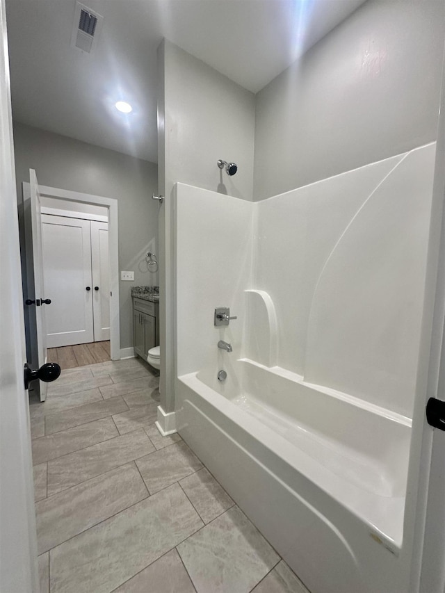 full bathroom with baseboards, visible vents, toilet, wood finish floors, and washtub / shower combination