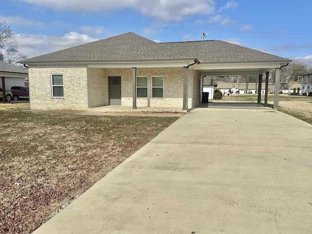 view of front of house with a shingled roof, concrete driveway, and brick siding