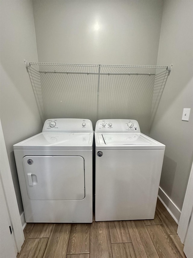 laundry area with light wood-type flooring, laundry area, washer and clothes dryer, and baseboards