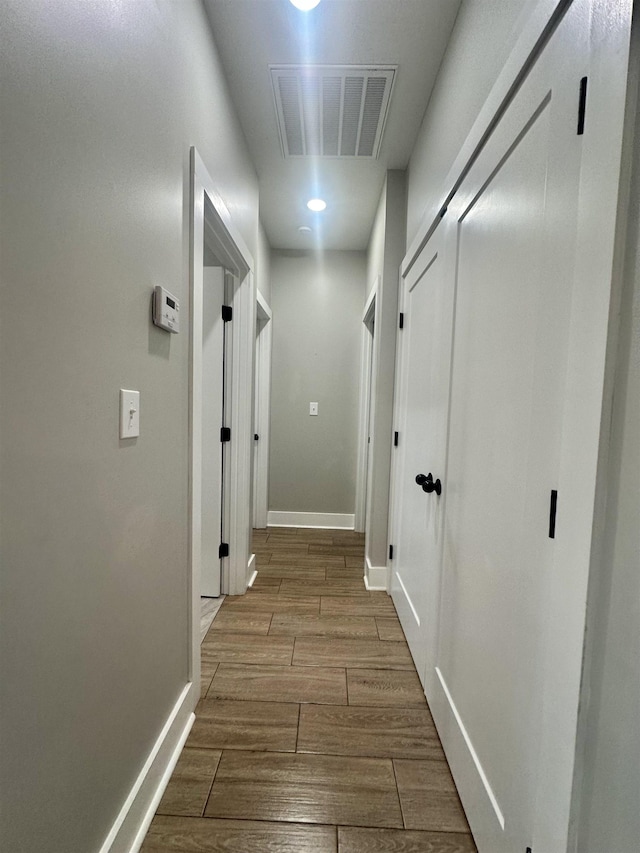 corridor with wood finish floors, visible vents, and baseboards