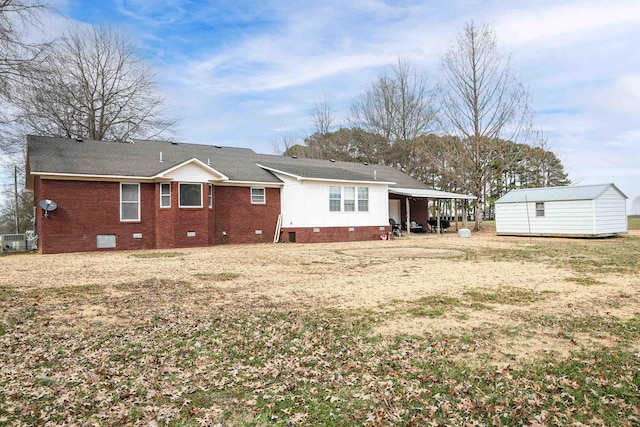 back of house with a storage shed, an outbuilding, crawl space, a carport, and brick siding