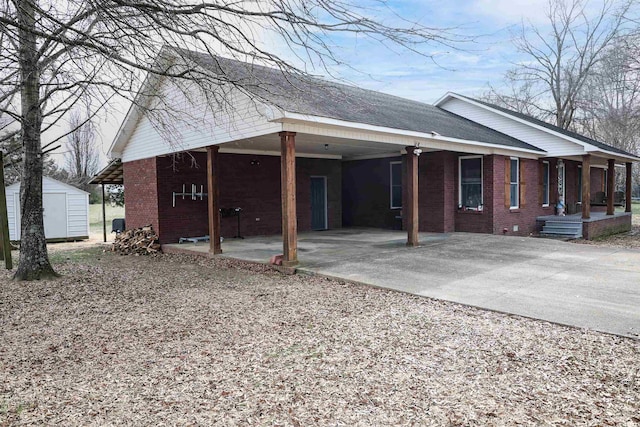 view of side of home featuring an outbuilding, brick siding, driveway, and a storage shed