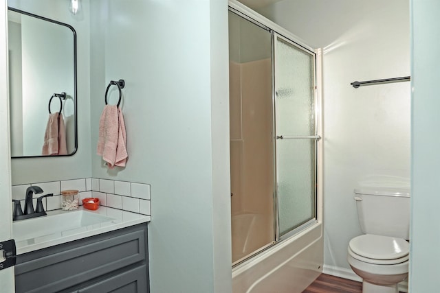 full bathroom with decorative backsplash, toilet, wood finished floors, combined bath / shower with glass door, and vanity