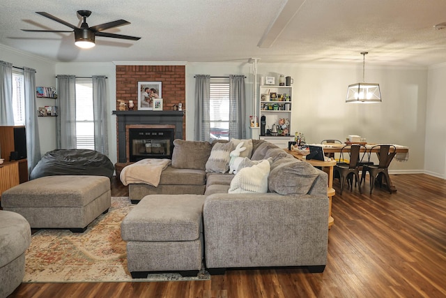 living room with dark wood-type flooring, a brick fireplace, plenty of natural light, and ornamental molding