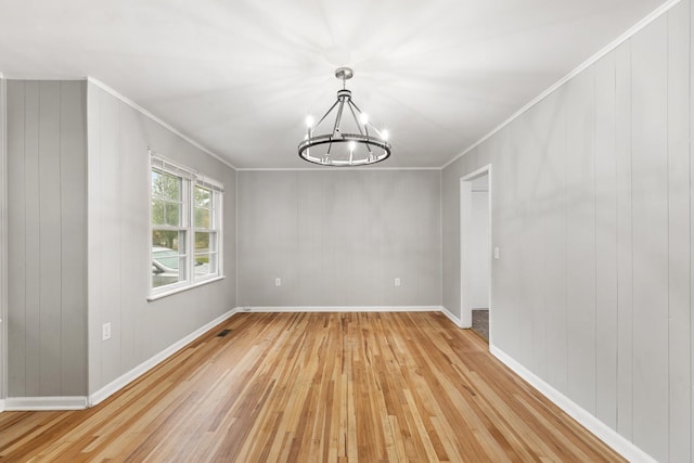 unfurnished dining area featuring crown molding, light hardwood / wood-style flooring, and an inviting chandelier