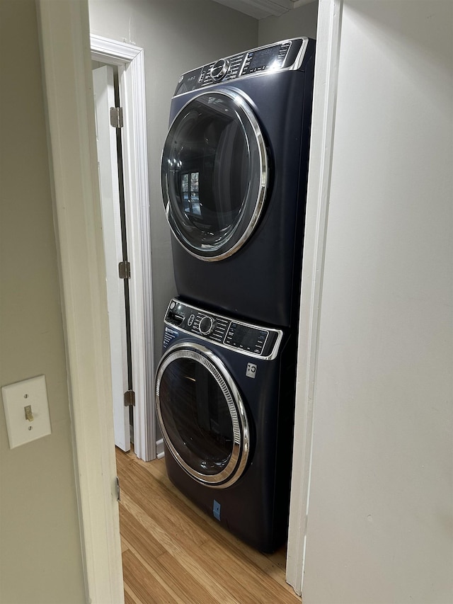 clothes washing area with light wood-type flooring and stacked washing maching and dryer