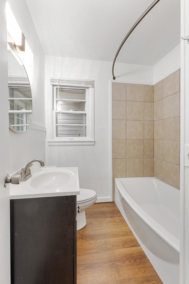 full bathroom featuring tiled shower / bath, vanity, wood-type flooring, and toilet