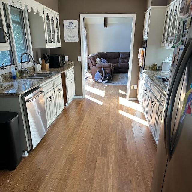 kitchen featuring white cabinets, stainless steel appliances, sink, light hardwood / wood-style flooring, and stone counters